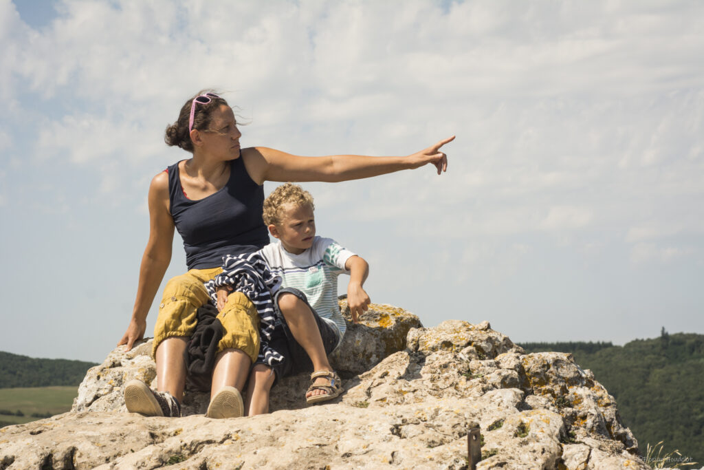photo de famille spontanée et complice d'une maman et son enfant sur le rocher regarde l'horizon